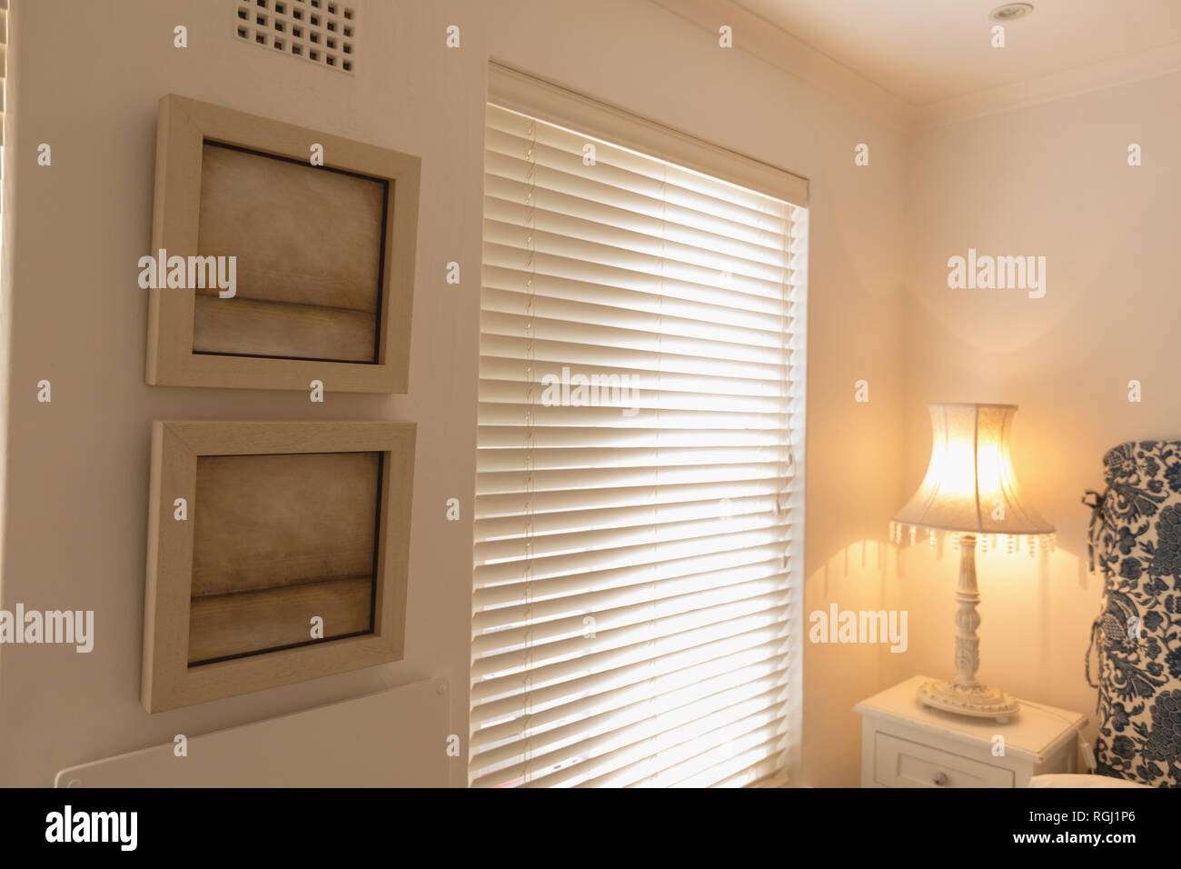 Wall frames near window blinds at home Stock Photo
