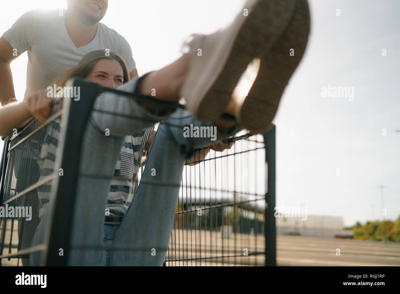 Carefree young man pushing girlfriend in a shopping cart Stock Photo