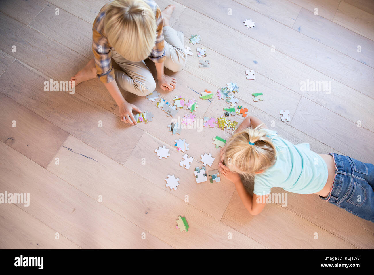 Brother and sister lying on the floor at home playing jigsaw puzzle Stock Photo
