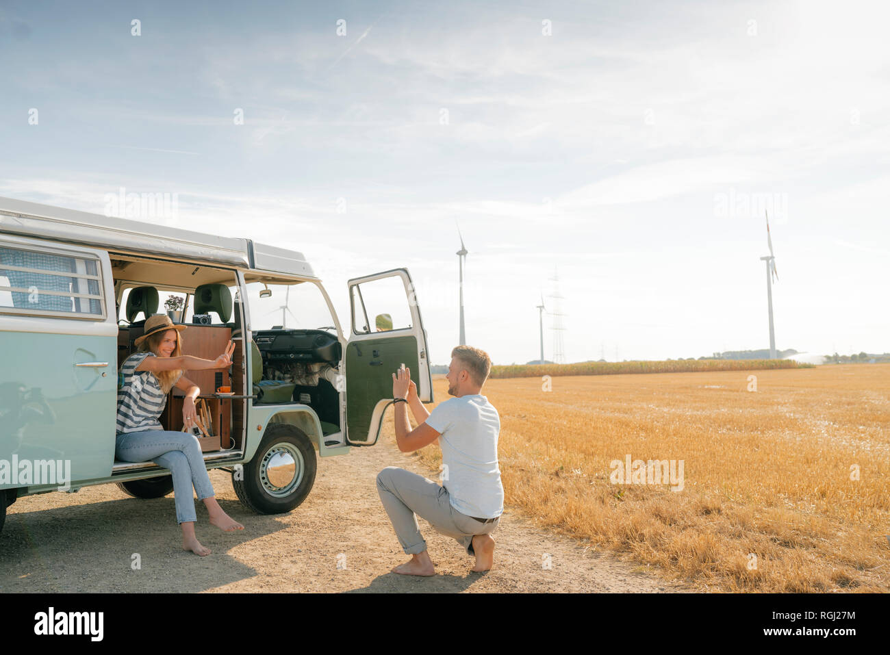 Happy young couple taking cell phone picture at camper van in rural ...