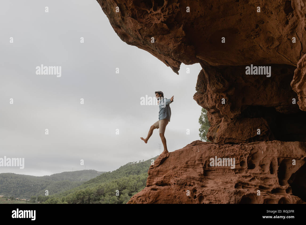 Young man balancing on the edge of an abyss Stock Photo