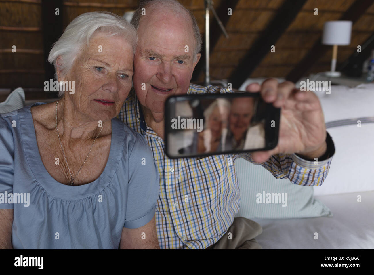 Front view of a senior couple taking a selfie with mobile phone in ...