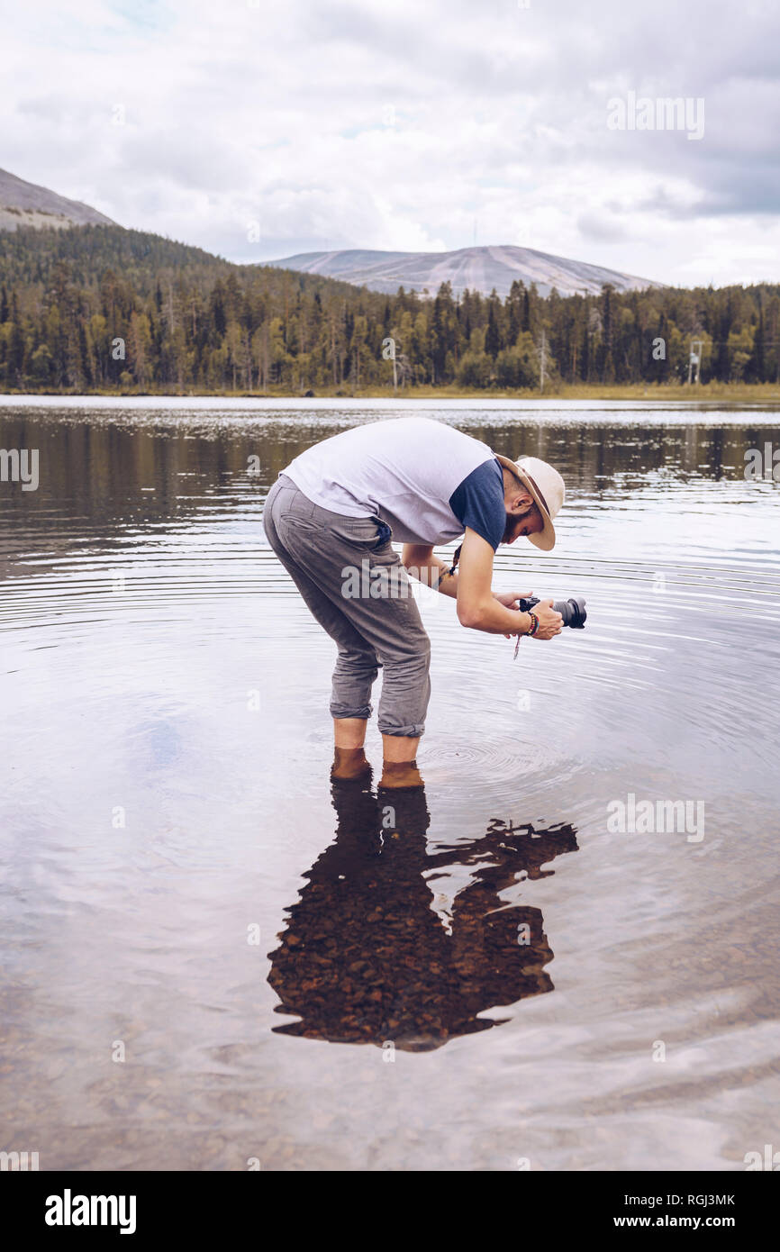 Sweden, Lapland, man standing in water taking photos Stock Photo