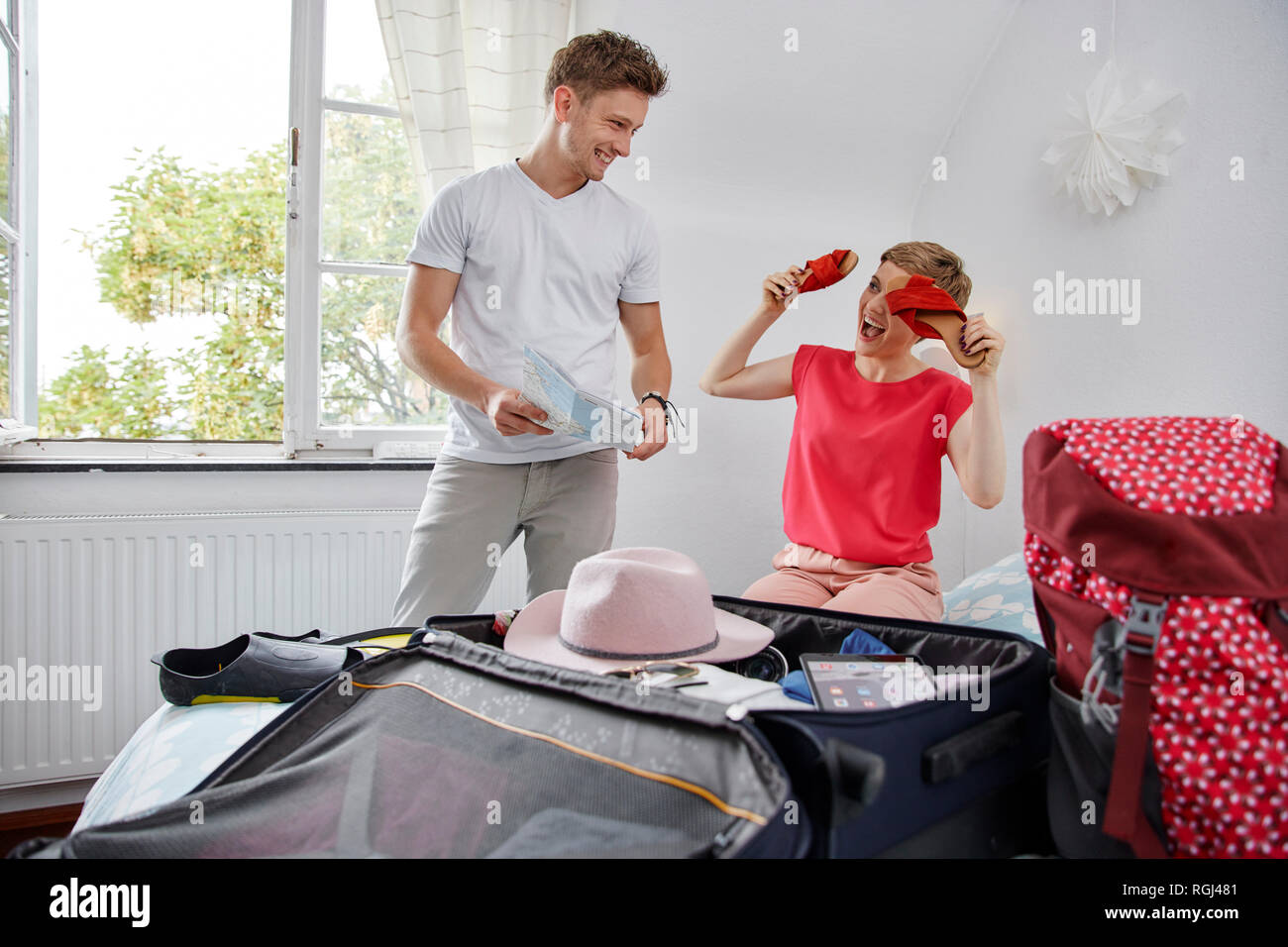 Happy couple packing suitcase for summer vacation on bed Stock Photo