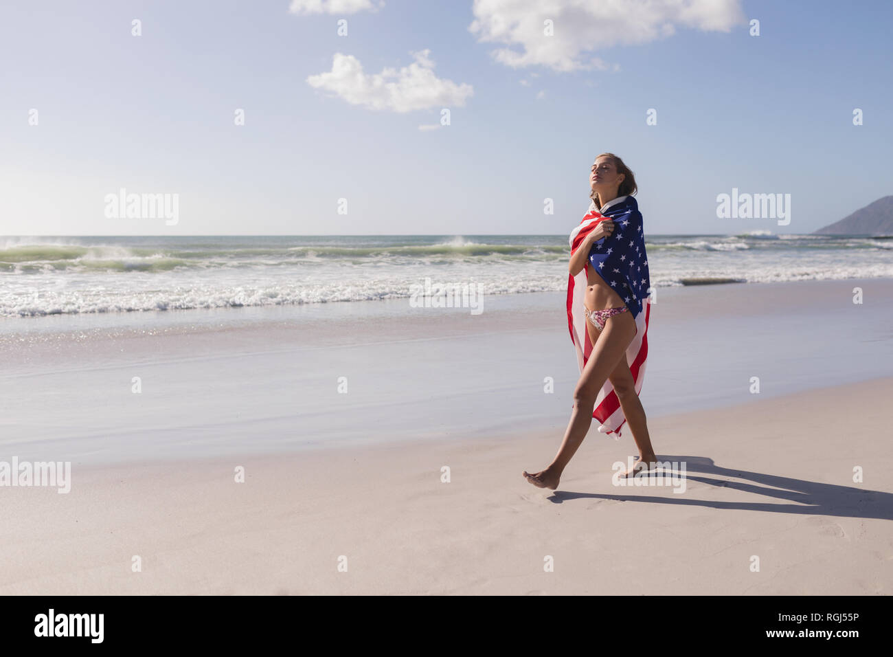 Young woman wrapped in American flag at beach Stock Photo - Alamy