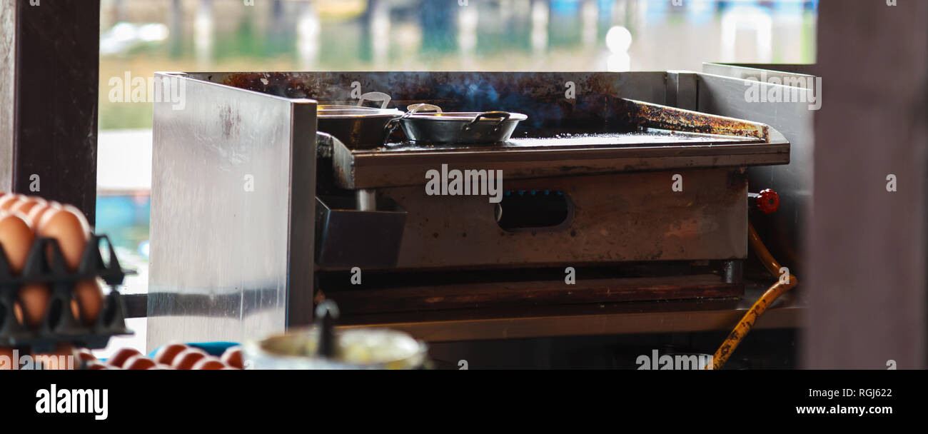 fresh smoking food in stainless steel pans on hot gas fueled stove