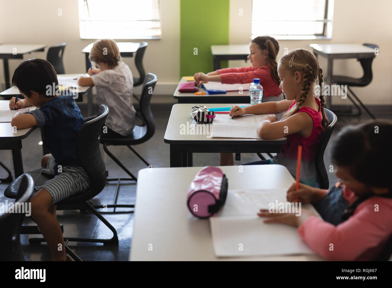 Kids studying in classroom sitting at desks in school Stock Photo