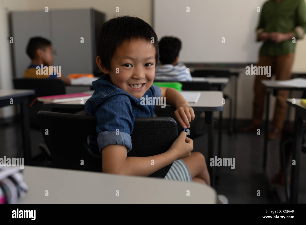 Happy schoolboy looking back in classroom Stock Photo