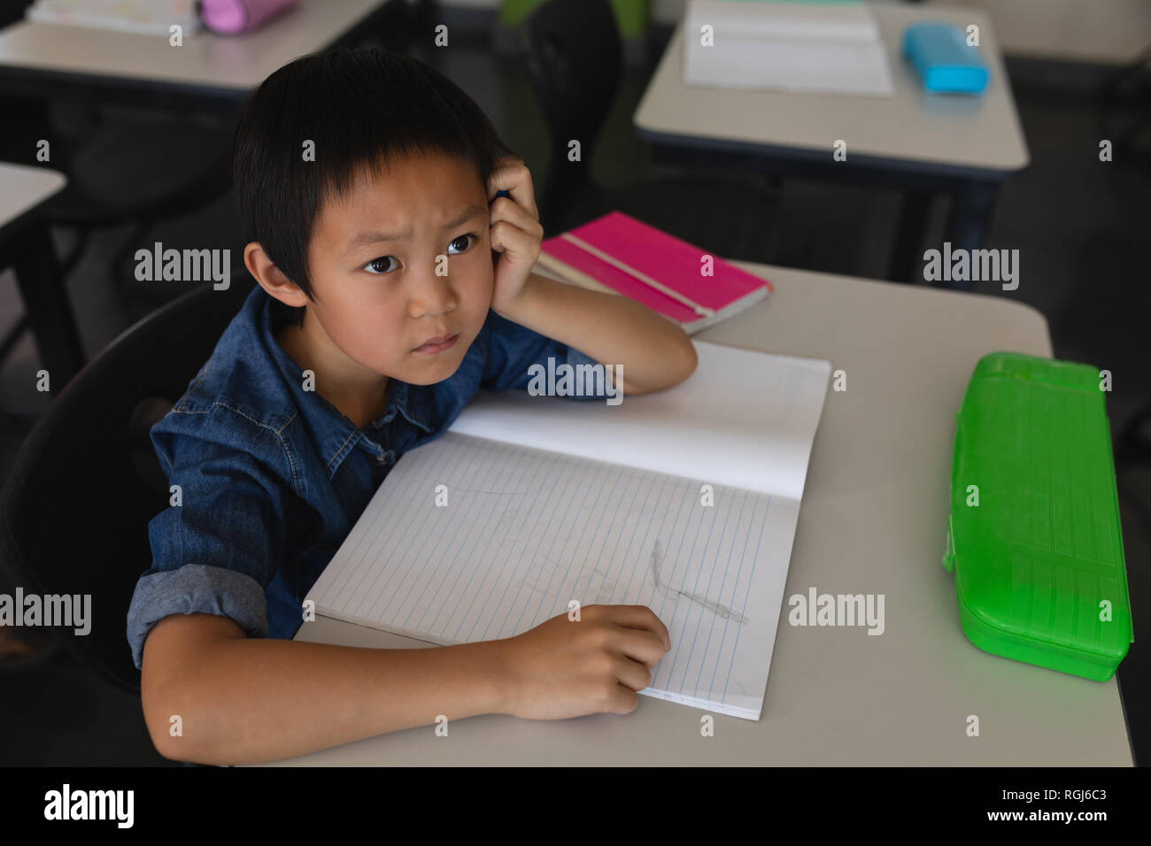 Schoolboy looking away in classroom Stock Photo