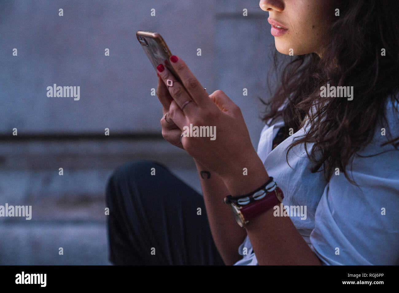 Young woman using cell phone at twilight, partial view Stock Photo