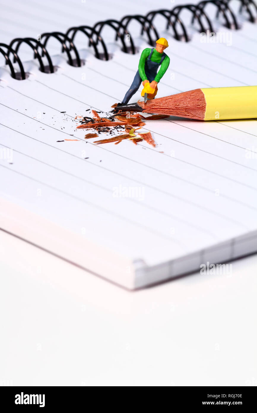 Conceptual diorama image of a miniature figure sharpening a pencil on a ...