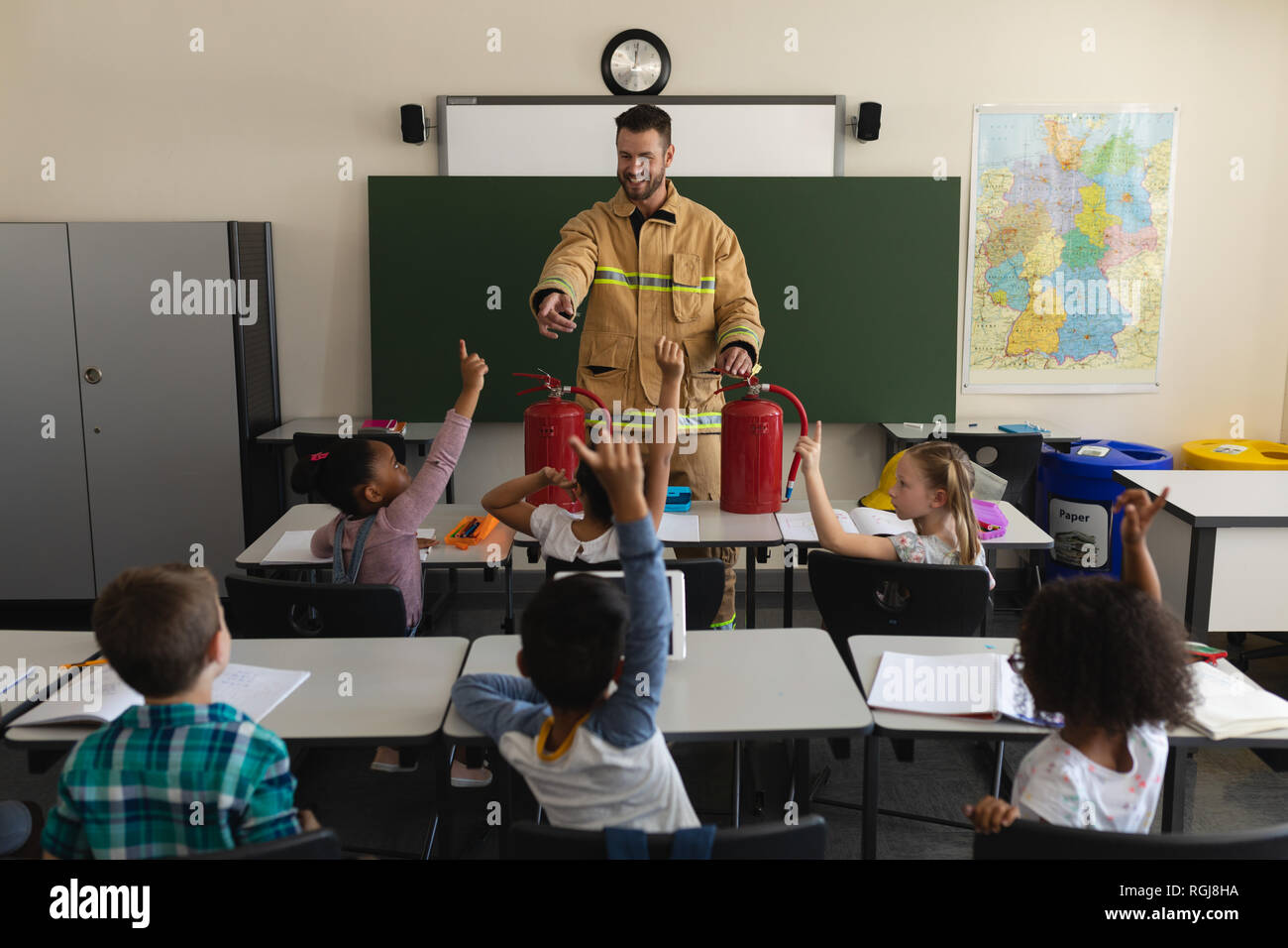Front view of a schoolkids raising hands while male Caucasian