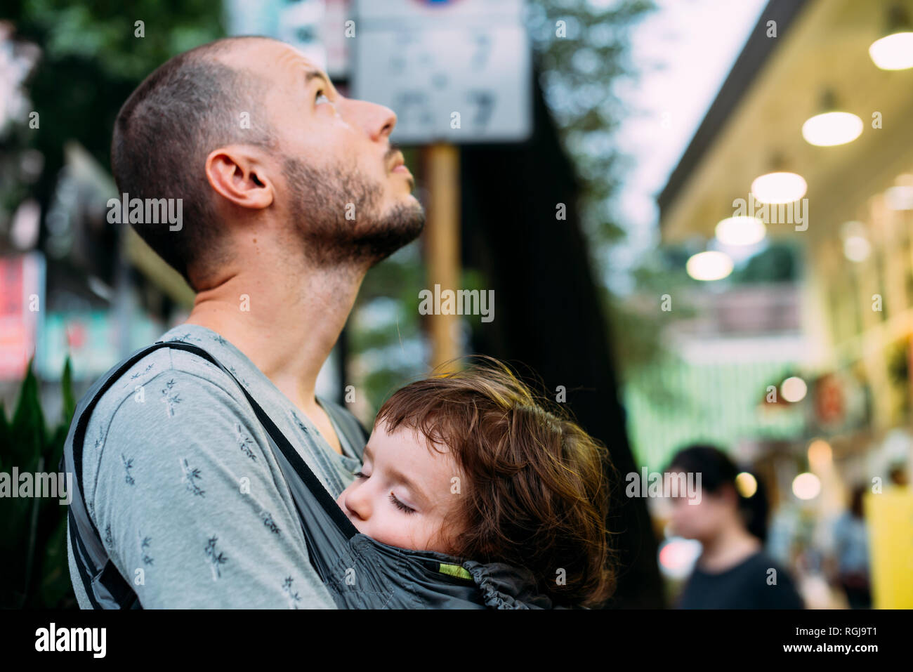 China, Hong Kong, father travelling with little girl sleeping in a baby carrier Stock Photo
