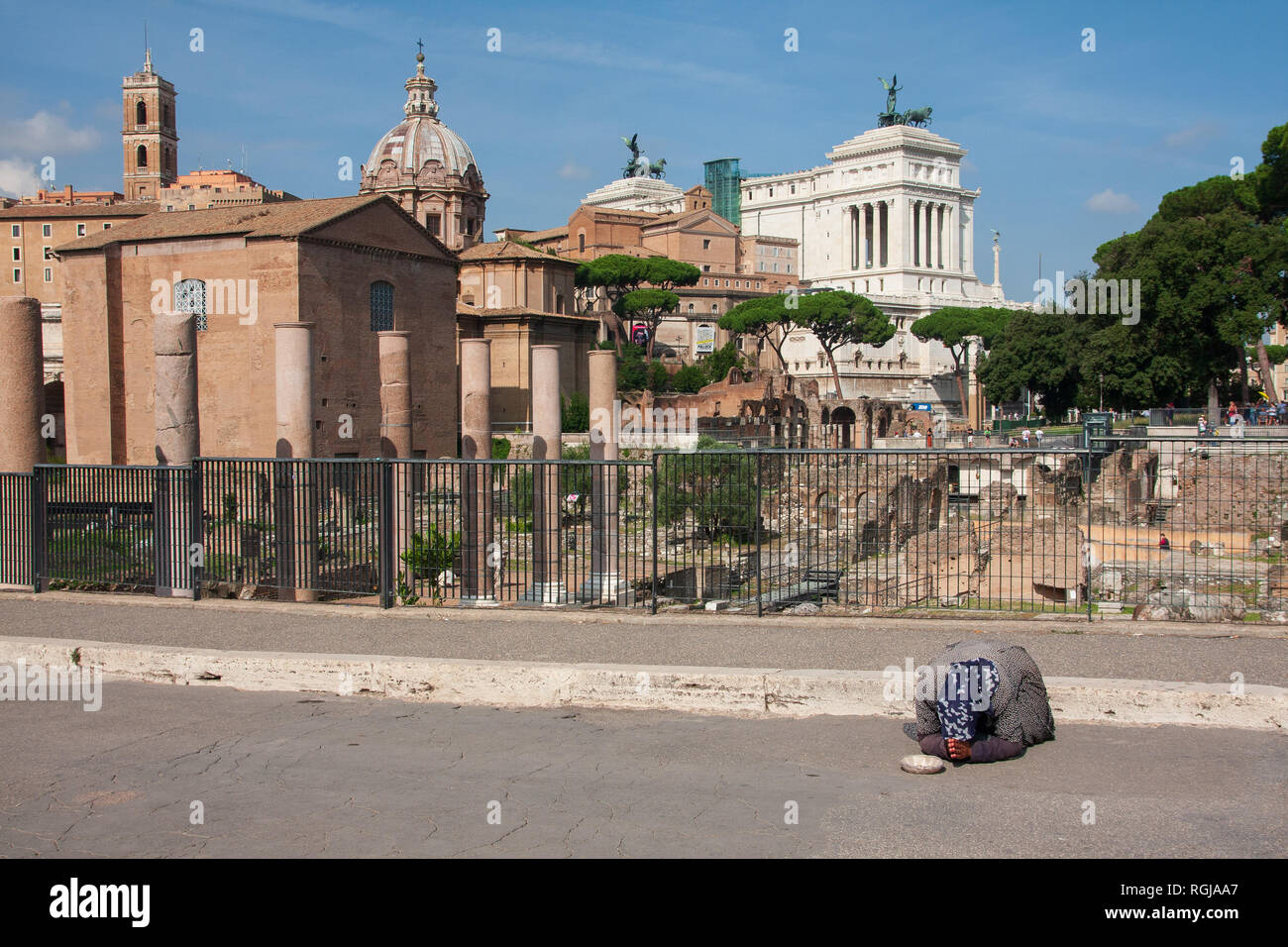 Old lady begging on road in front of Forums Rome Stock Photo