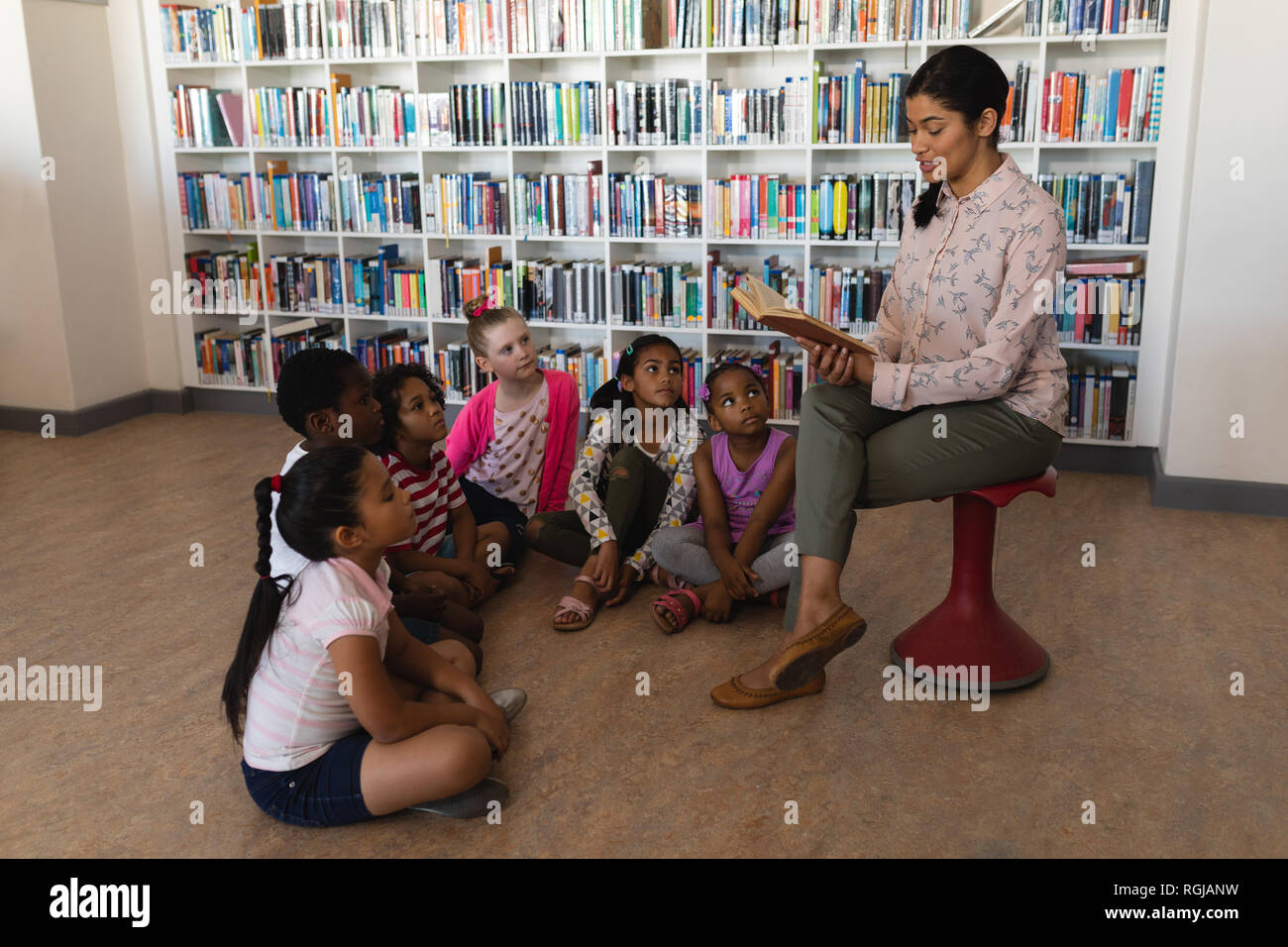 Side view of female teacher sitting on chair and reading a story