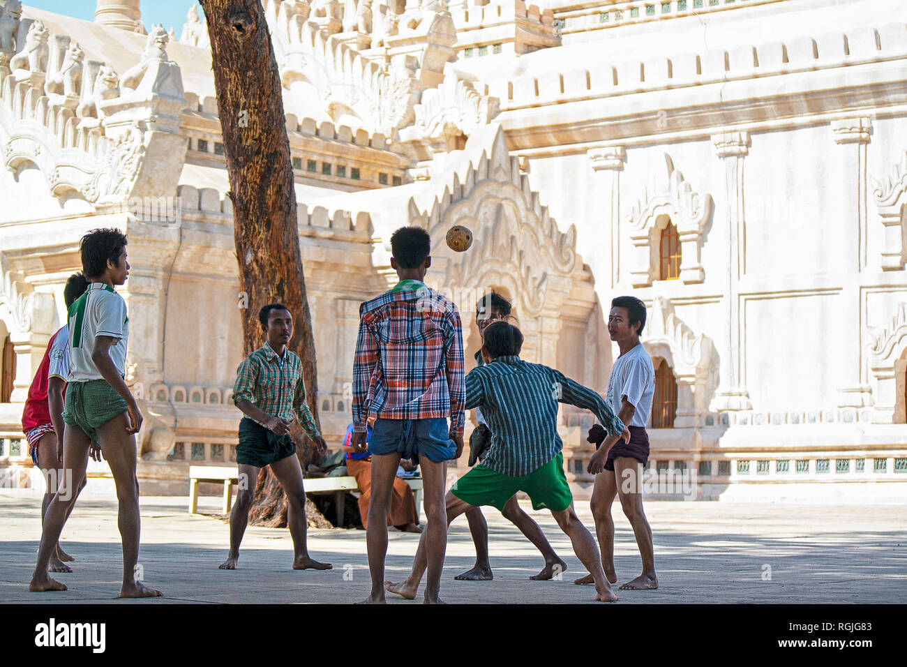 A group of men play Sepak takraw or kick volleyball or Chin Lone as it is known in Myanmar in the court yard of a Bagan temple. Stock Photo