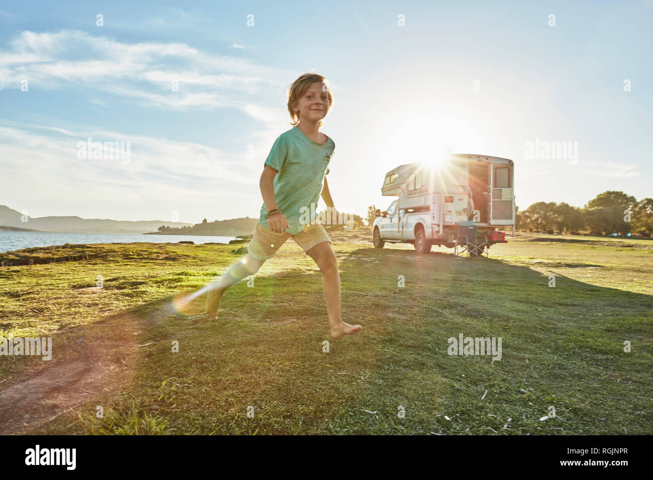 Chile, Talca, Rio Maule, boy running on meadowbeside camper at lake Stock Photo