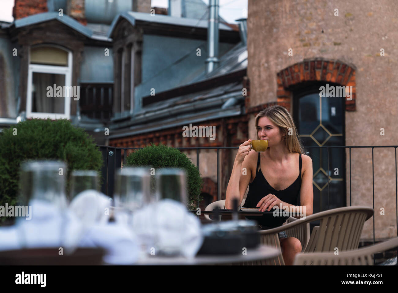 Young woman sitting on roof terrace drinking cup of coffee Stock Photo ...