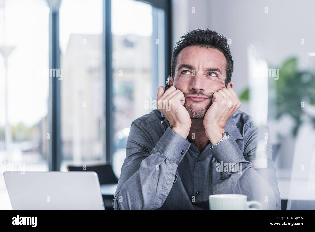 Businessman sitting in office, thinking Stock Photo