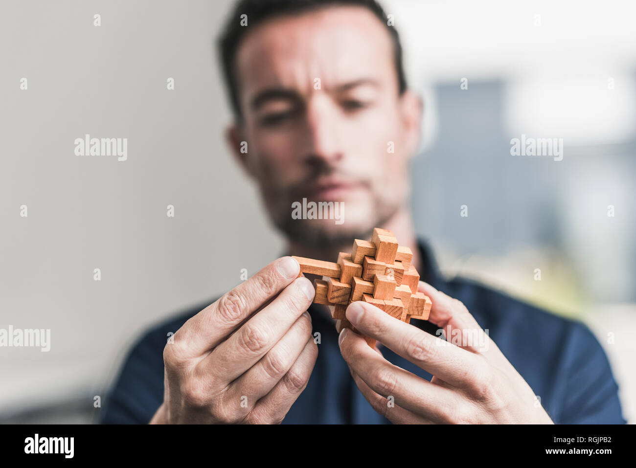 Mature man sitting in office assembling wooden cube puzzle Stock Photo