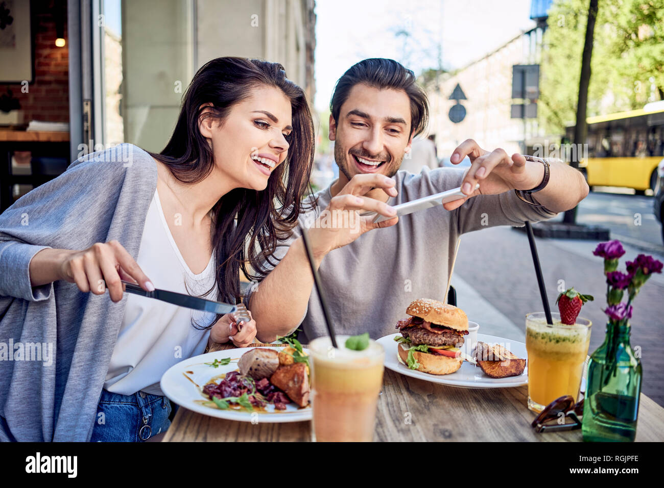 Happy young couple taking photo of food at outdoors restaurant Stock Photo
