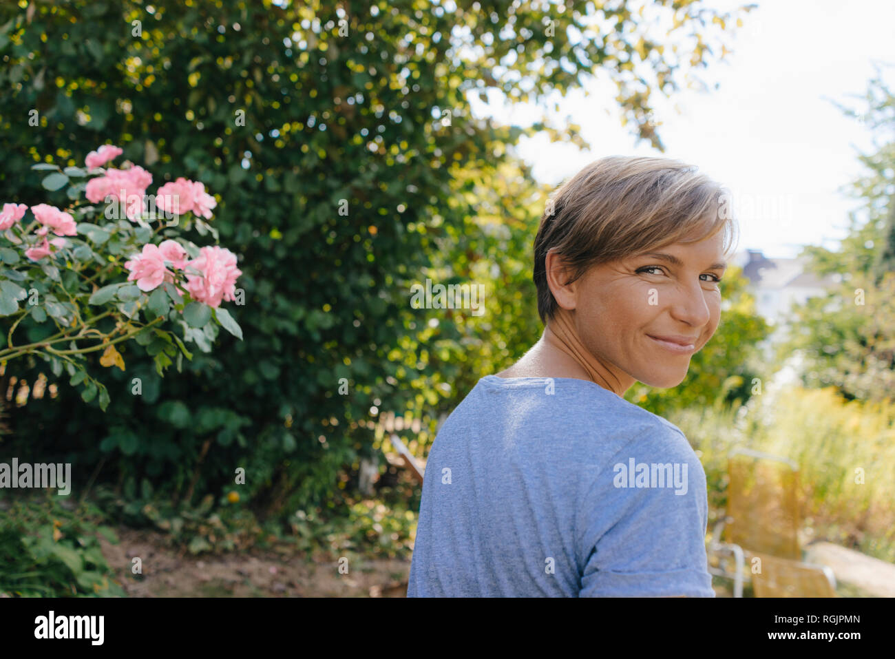 Portrait of smiling woman in garden turning round Stock Photo