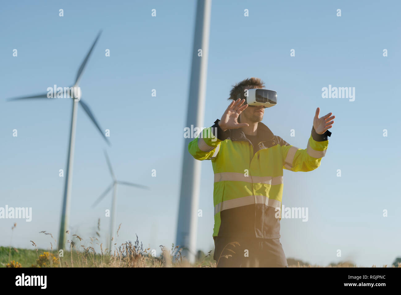 Engineer standing in a field at a wind farm wearing VR glasses Stock Photo