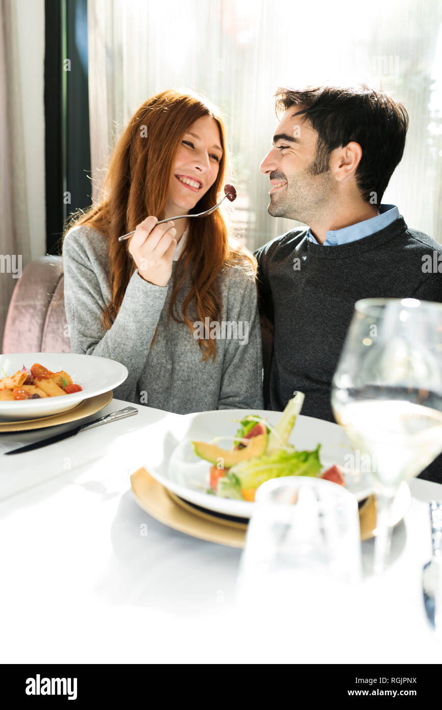 Smiling woman letting man taste the food in a restaurant Stock Photo