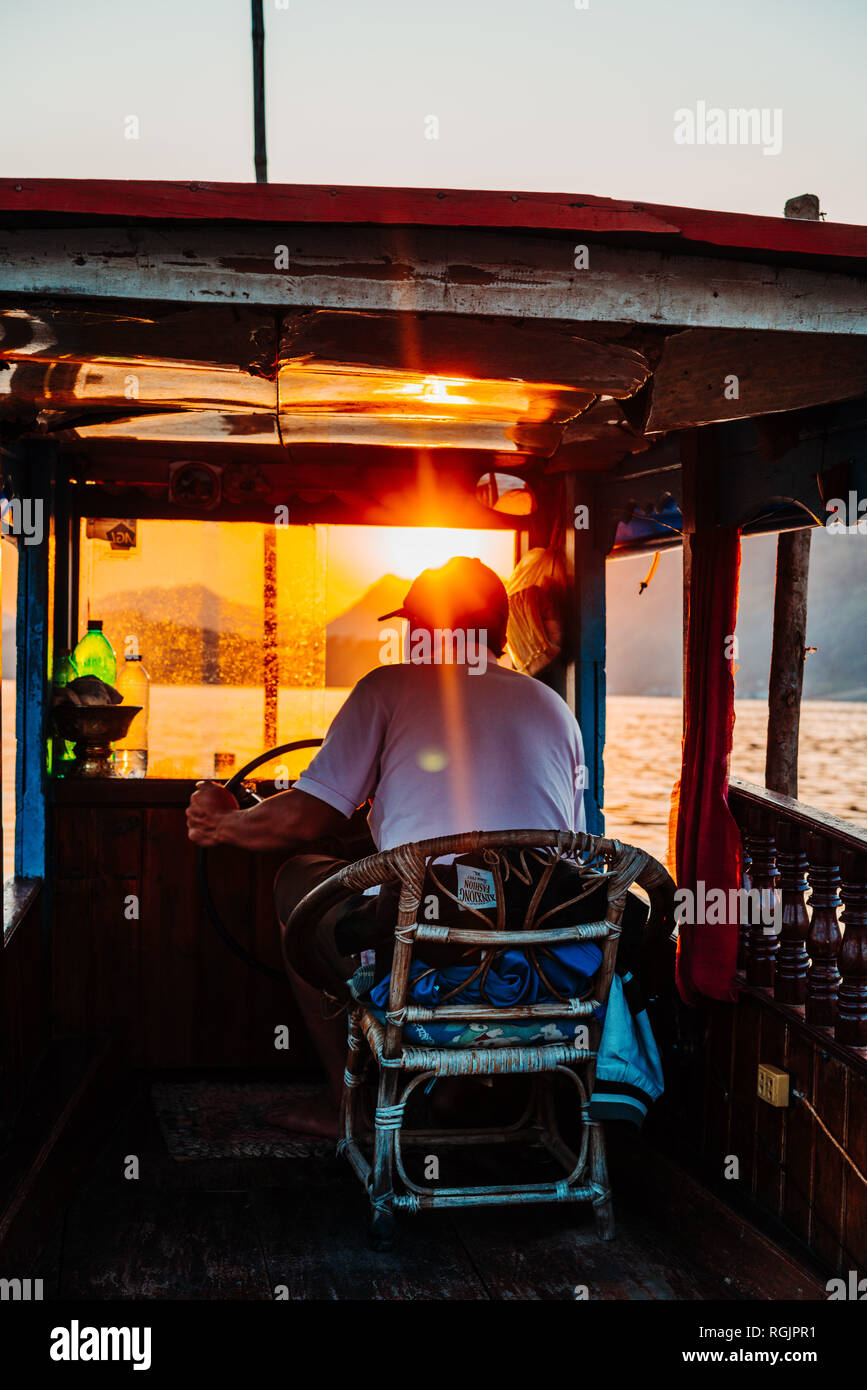 Luang Prabang, Laos, 12.19.18: Captain on ship takes tourists on a sunset cruise at the Mekong river. Beautiful sunset inlaos. Stock Photo