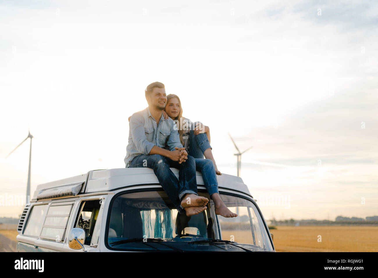 Smiling young couple on roof of a camper van in rural landscape Stock ...