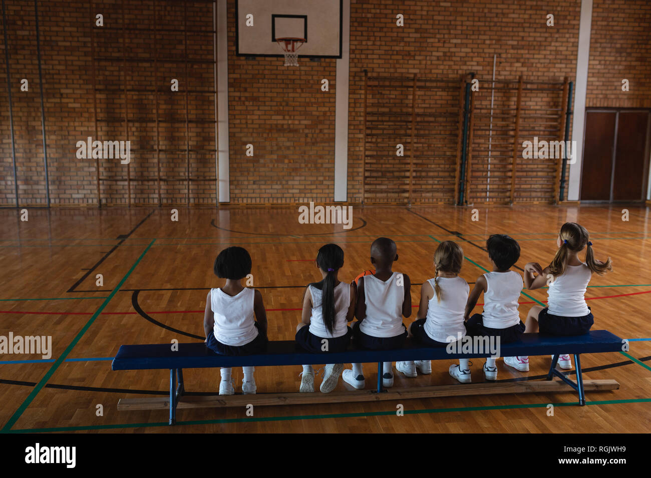 Schoolkids sitting on bench at basketball court Stock Photo Alamy