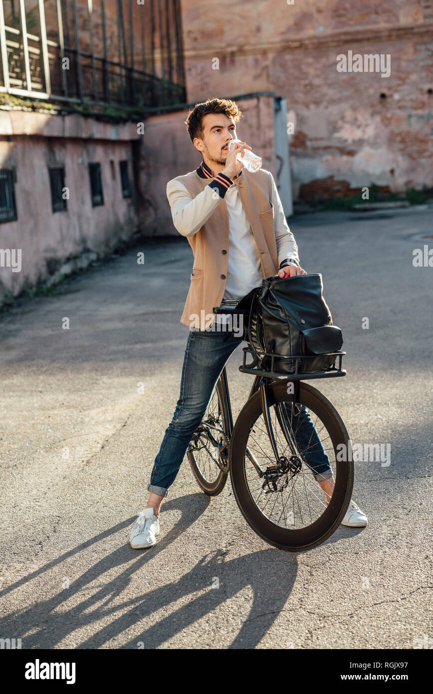 Young man with commuter fixie bike having a break on a backyard in the city Stock Photo