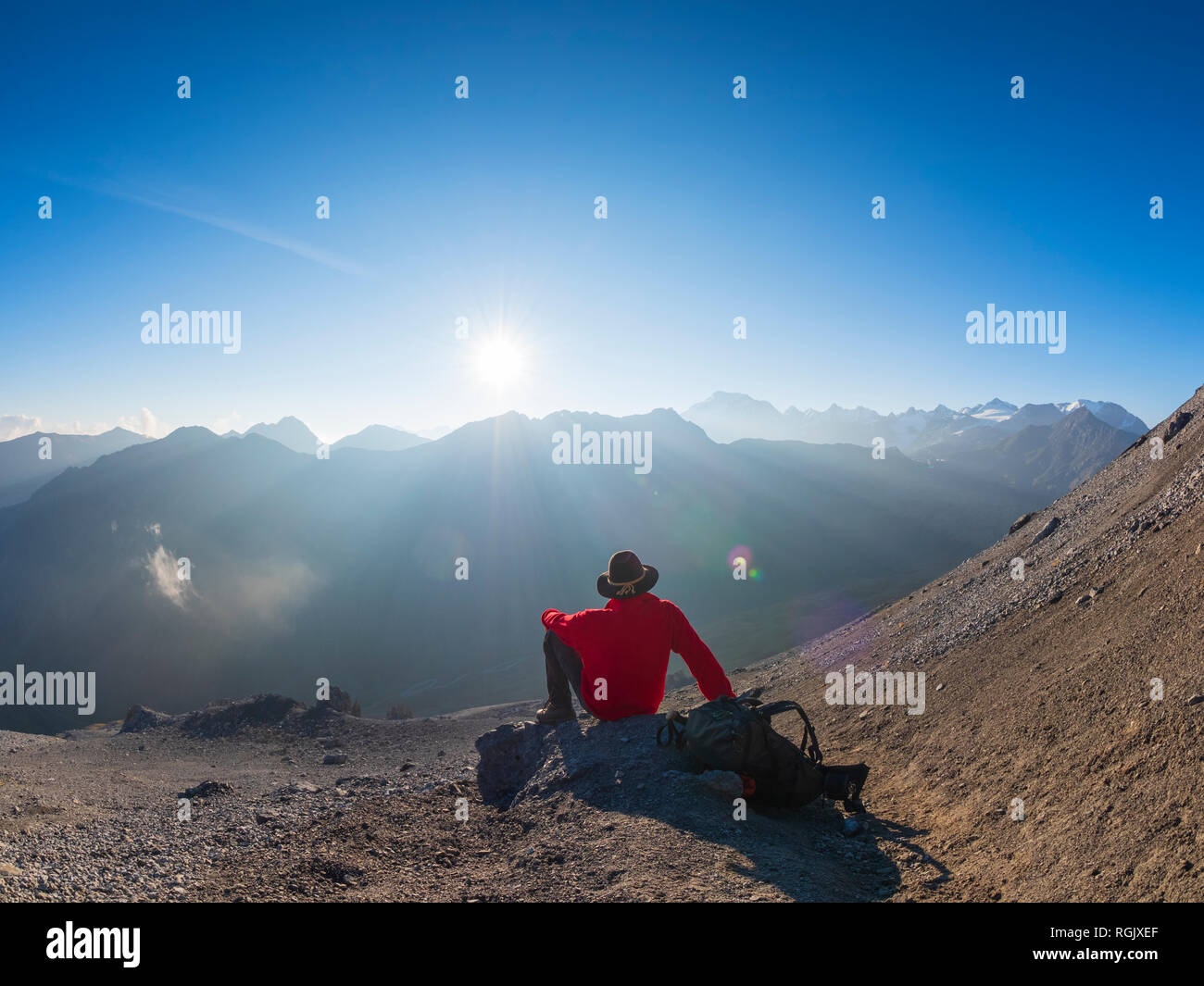 Border region Italy Switzerland, senior man having a break from hiking in mountain landscape at Piz Umbrail Stock Photo