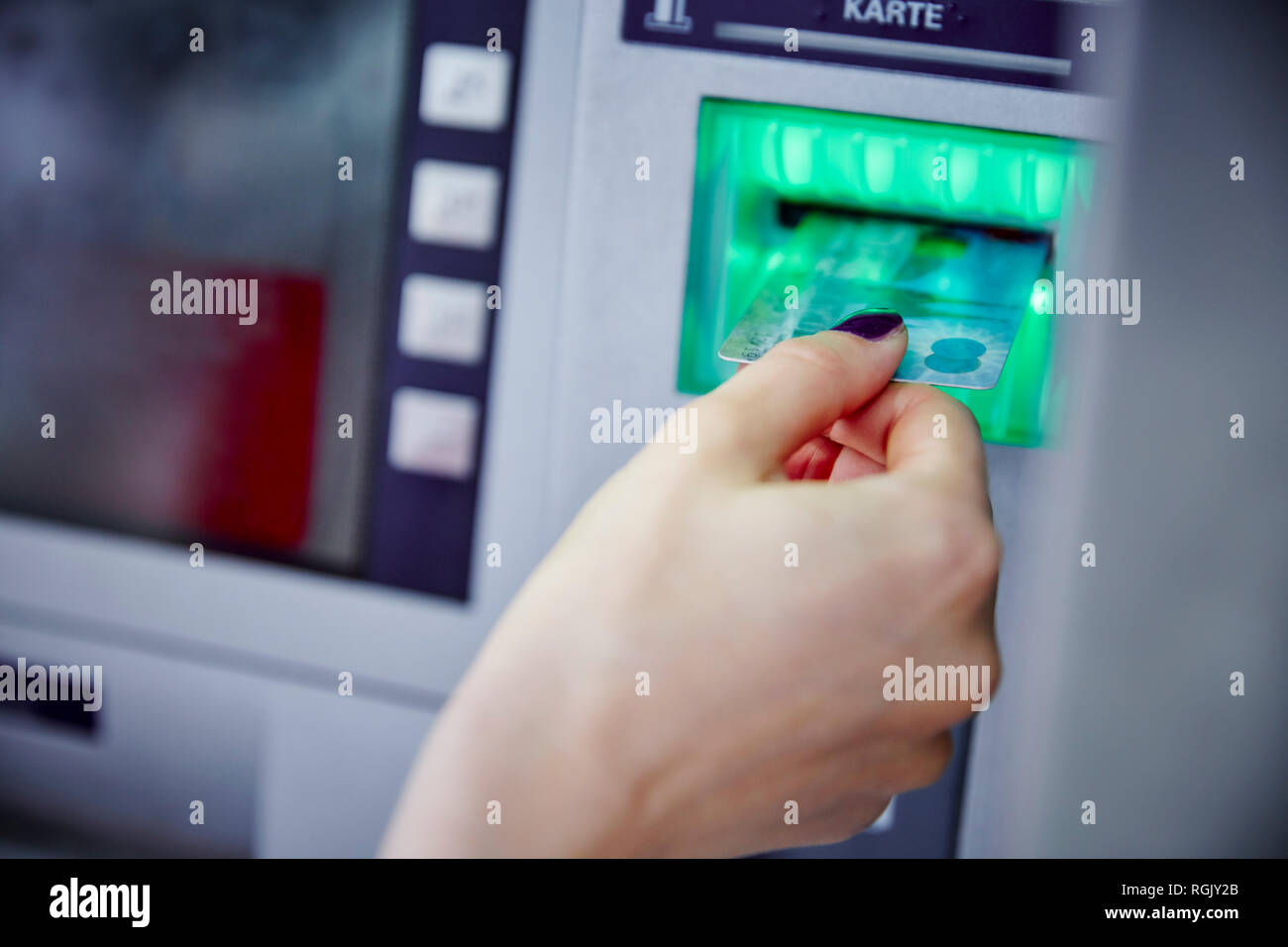 Close-up of woman putting card into slot of cash machine Stock Photo