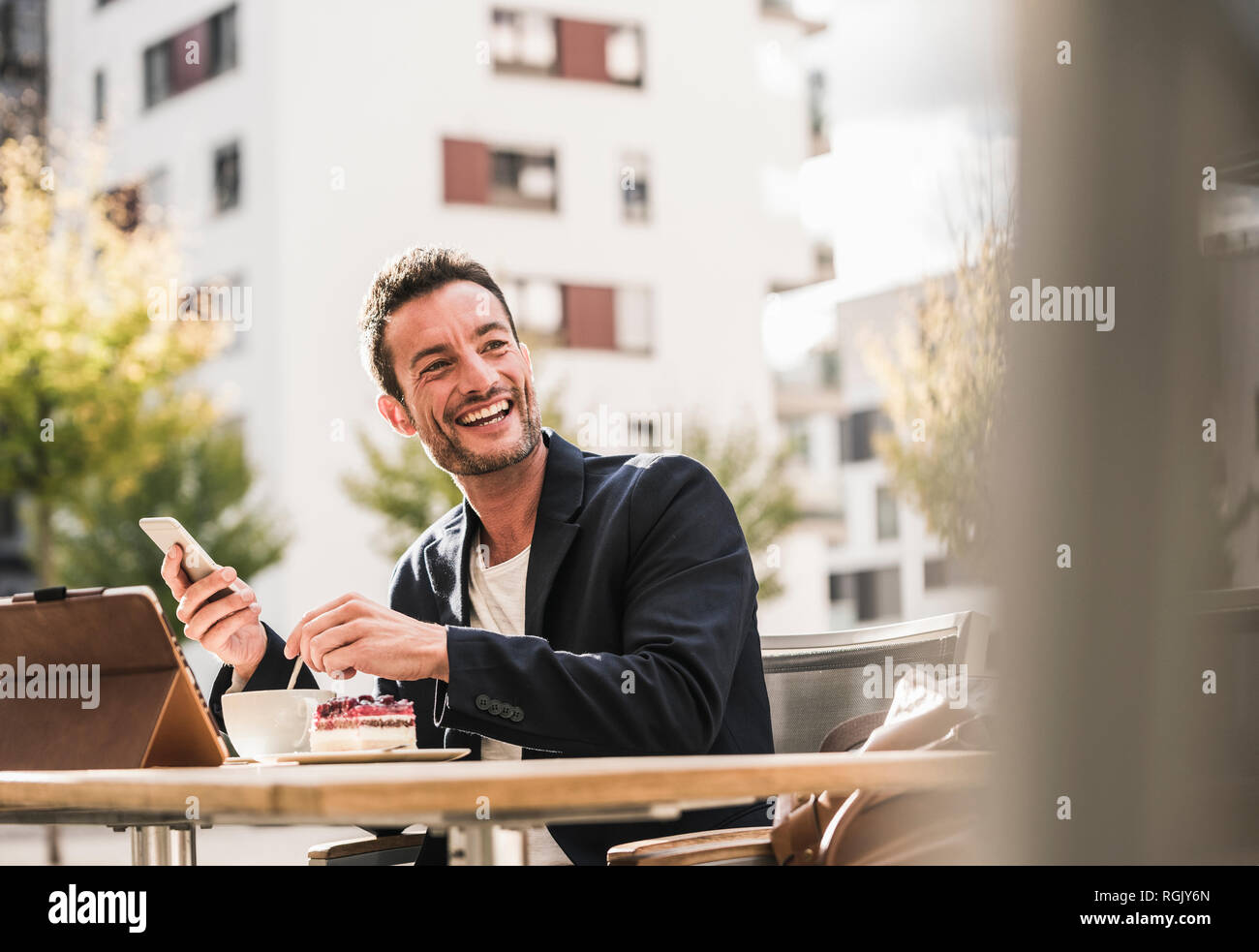 Businessman sitting in cafe, drinking coffee, using smartphone Stock Photo