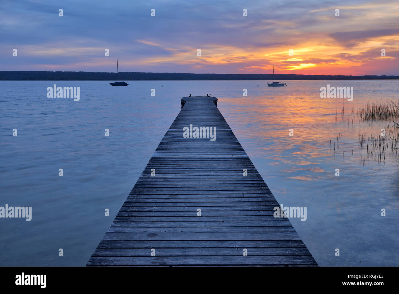 Wooden jetty at sunset at Lake Ammersee, Fuenfseenland, Bavaria, Germany. Stock Photo