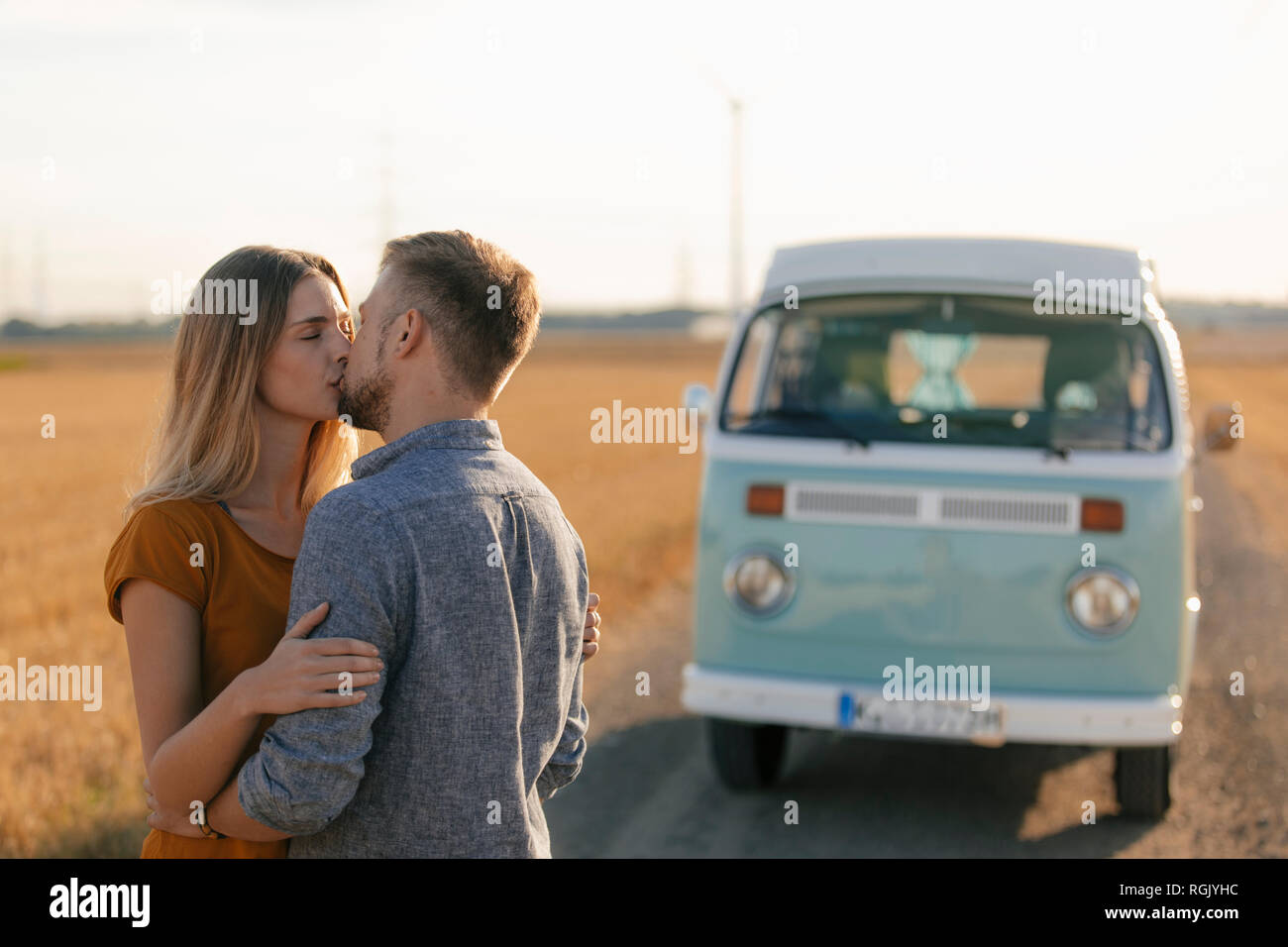 Young couple kissing at camper van in rural landscape Stock Photo