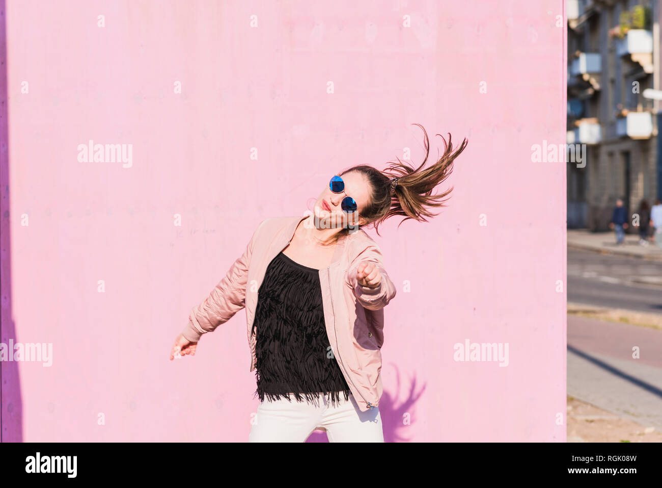 Happy young woman moving in front of pink wall Stock Photo - Alamy