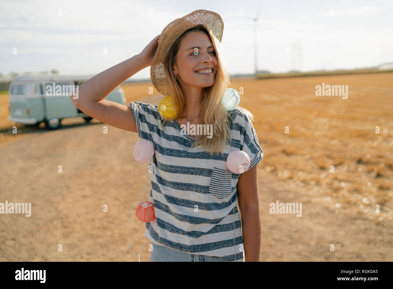 Happy young woman at camper van in rural landscape Stock Photo