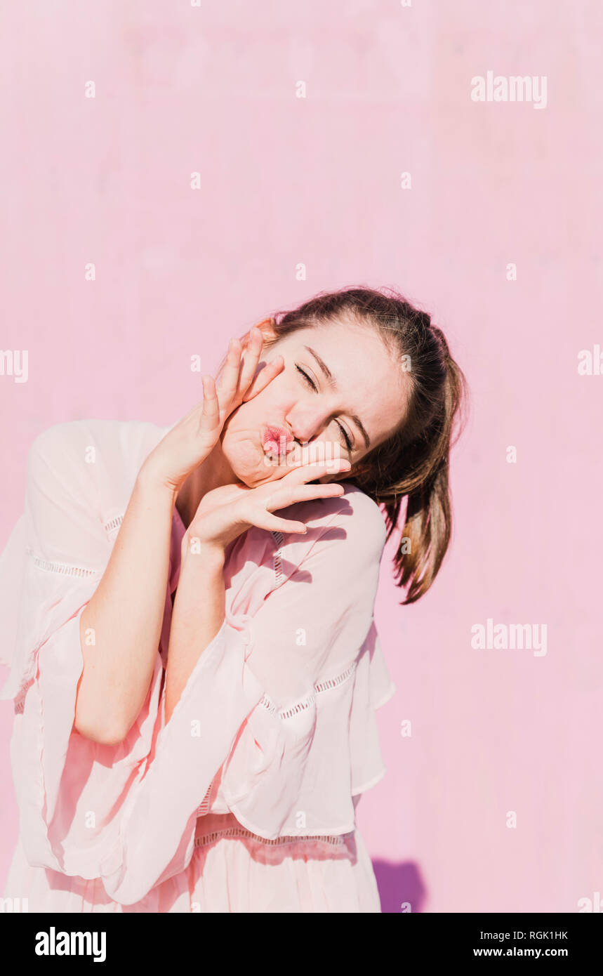 Portrait of young woman grimacing in front of pink wall Stock Photo - Alamy