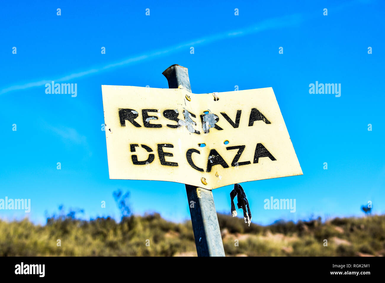 Hunting reserve signal in Spain. Sunny day. Leaky and rusty metal plate. Blue sky Stock Photo