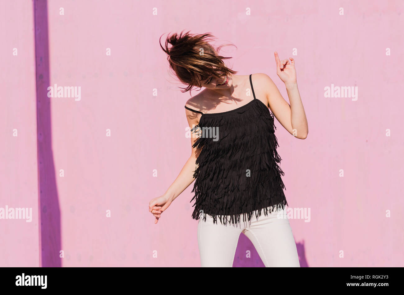 Happy young woman moving in front of pink wall Stock Photo - Alamy