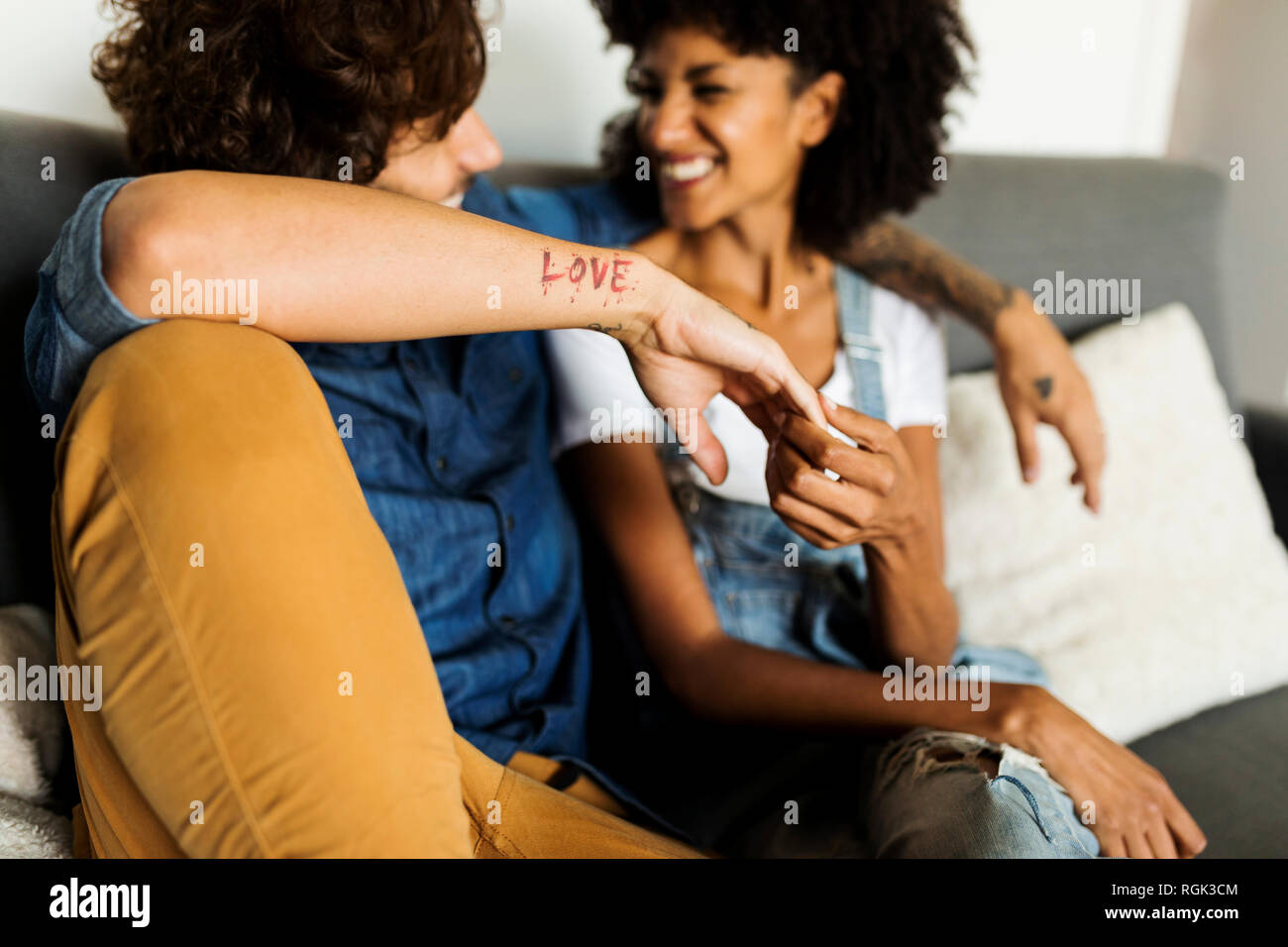 Happy couple sitting on couch talking Stock Photo