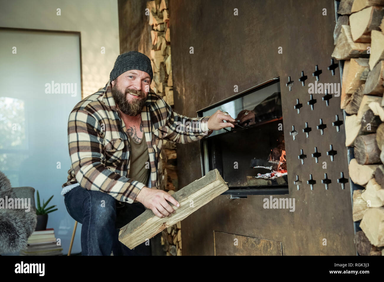 Portrait of bearded man lighting fireplace at home Stock Photo