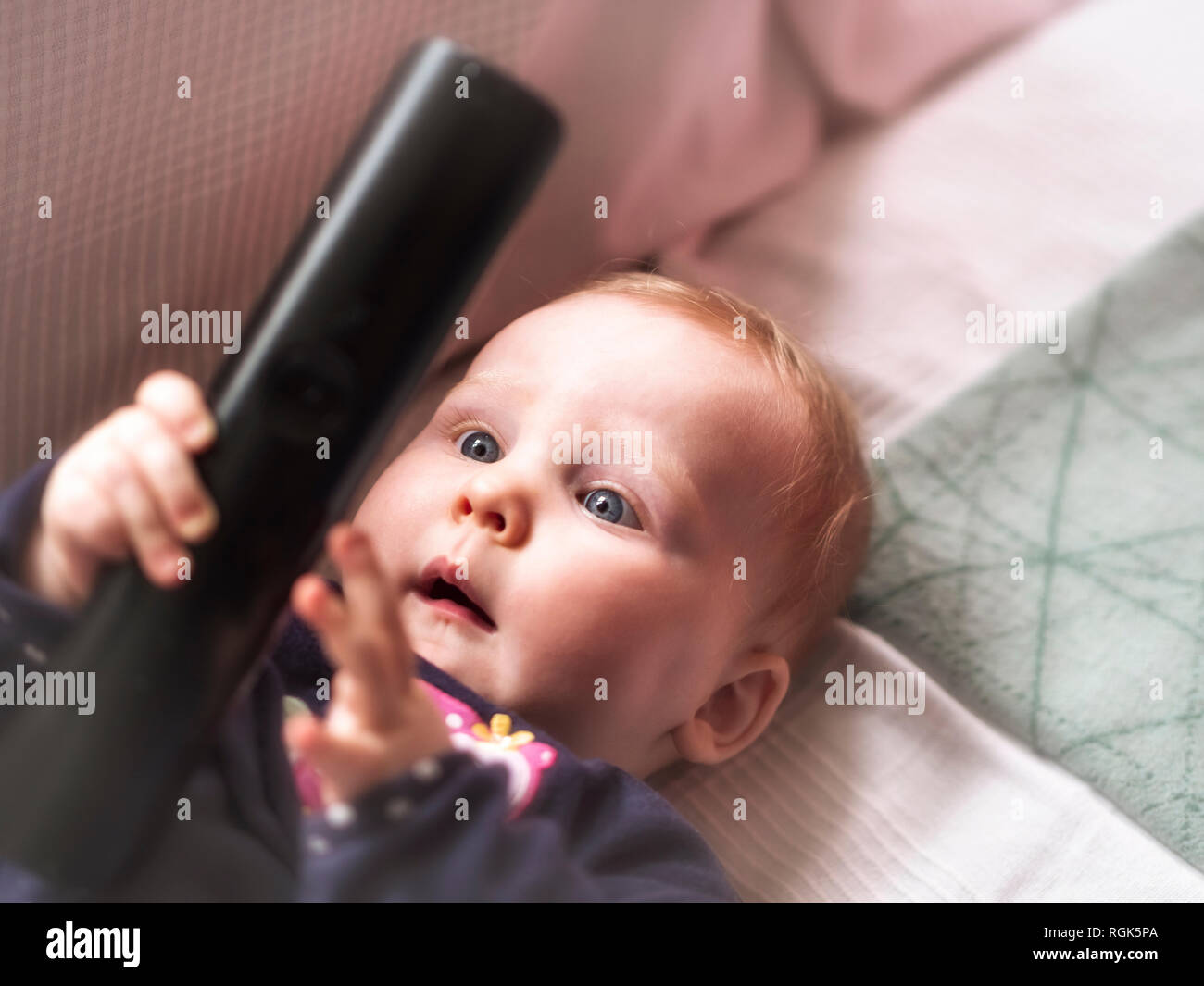 Baby girl holding remote control Stock Photo
