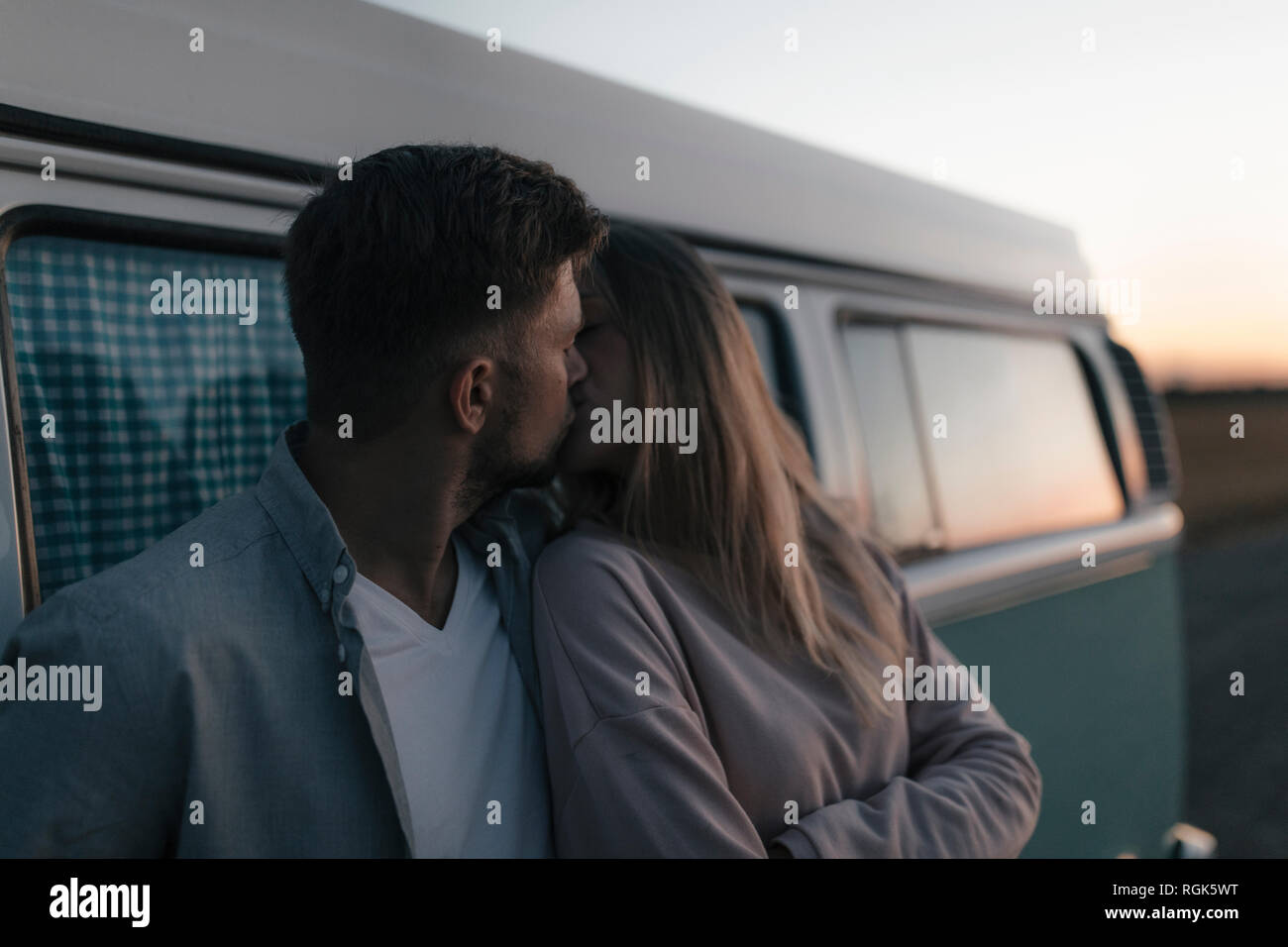 Young couple kissing at camper van at dusk Stock Photo - Alamy