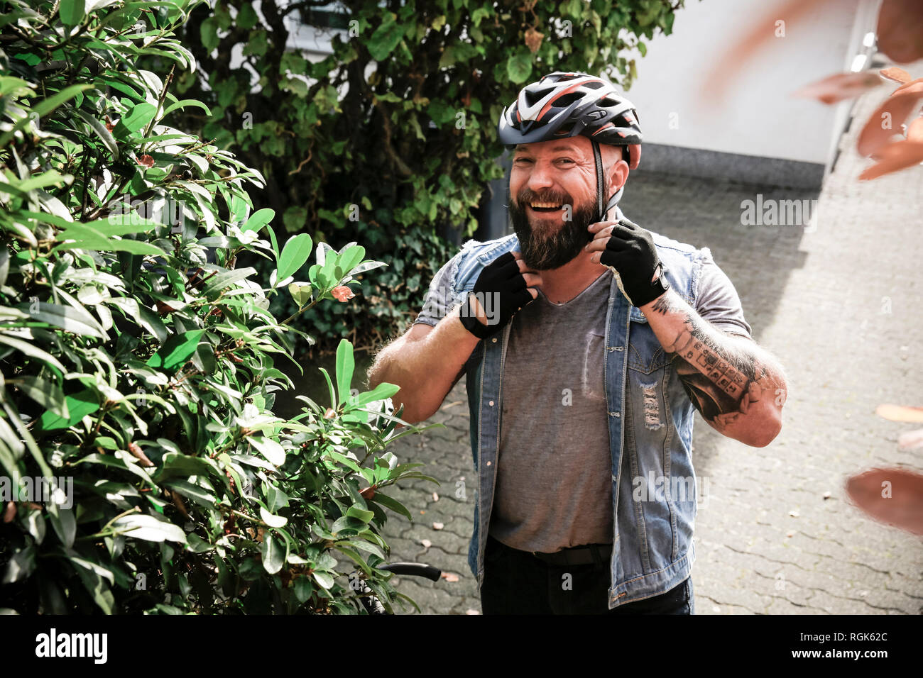 Portrait of laughing man putting on bicycle helmet Stock Photo