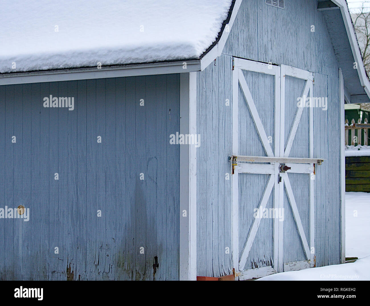 Snow topped light Blue with white trim wooden storage shed Stock Photo