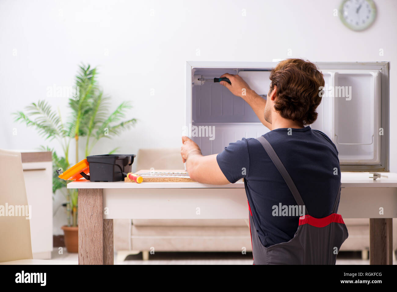 Young handsome contractor repairing fridge Stock Photo