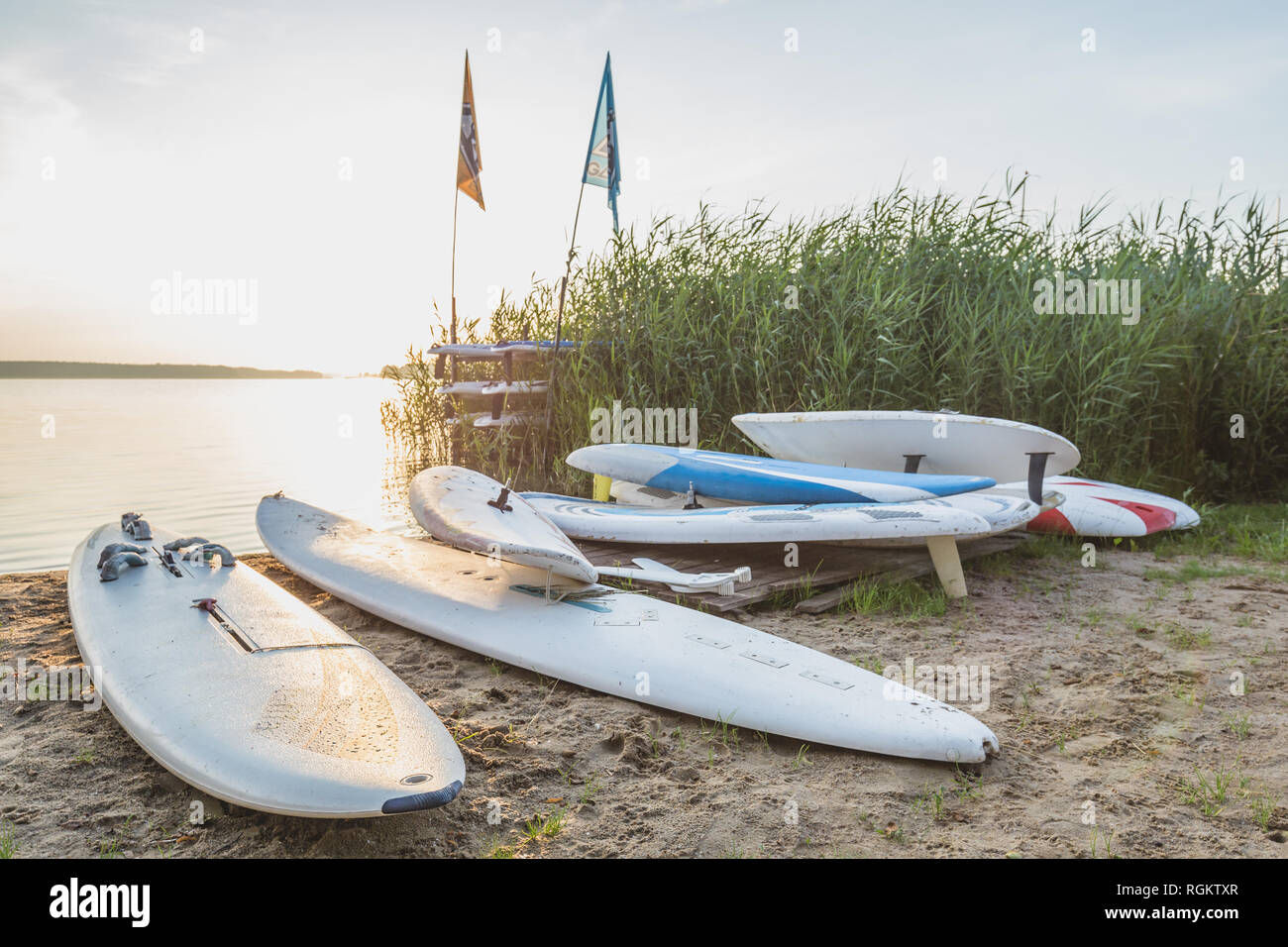 Old-school windsurfing boards on the shore of the lake. Stock Photo